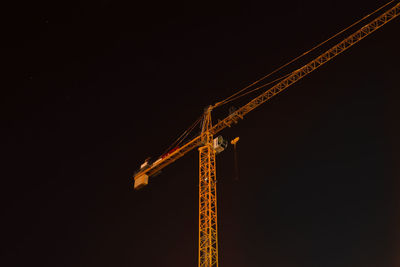 Low angle view of crane against sky at night
