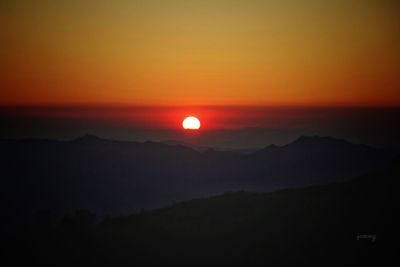 Scenic view of silhouette mountains against romantic sky at sunset
