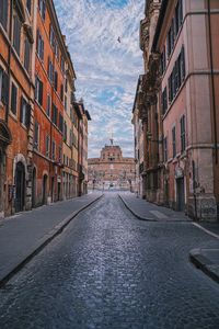 Empty road amidst buildings in city