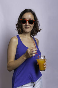 Mid adult woman wearing sunglasses standing against gray background