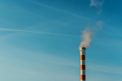 Smoke emitting from chimney against blue sky