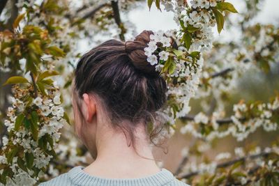 Rear view of woman standing by white flowers