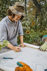 Male environmentalist drawing on blueprint at table