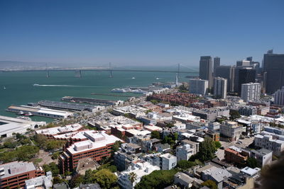 High angle view of buildings by sea against clear blue sky