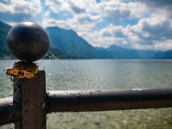 Close-up of railing by lake against sky