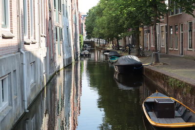 Boats moored in canal amidst buildings in city