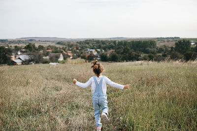 Woman with arms raised on field against sky