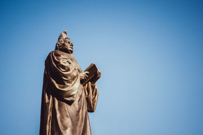 Low angle view of statue against blue sky