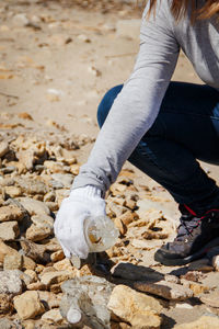 Low section of woman picking plastic bottle