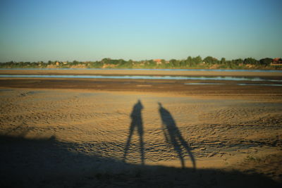 Shadow of people on beach against sky