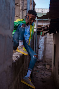 View of a young man sitting on a wall using a mobile phone 