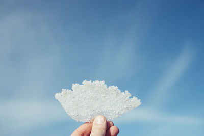 Close-up of person holding hand against sky