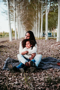 Full length of mother with daughter sitting at park