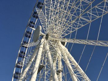 Low angle view of ferris wheel against clear blue sky