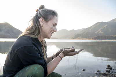 Woman putting mud on hands and face while enjoying outdoors in nature.