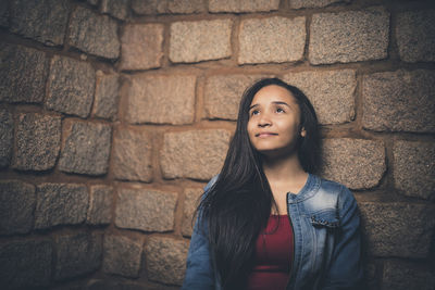 Teenager standing against brick wall