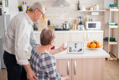 Rear view of couple talking with doctor on video call