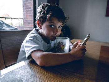 Midsection of man using mobile phone while sitting on table at home