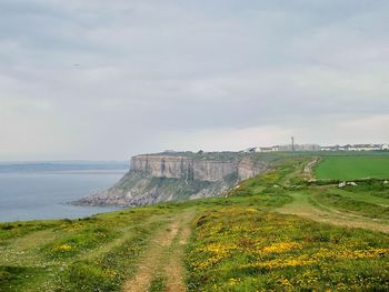 Scenic view of land by sea against sky
