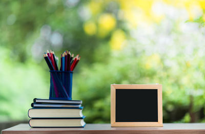 Close-up of colored pencils in desk organizer with books and blackboard at home