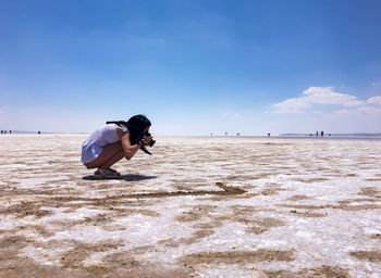 Man photographing at beach against sky