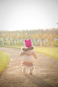 Rear view of girl standing on field against sky