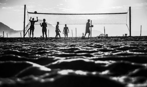 Silhouette people at beach against sky