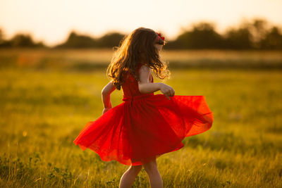 Girl walking on field against sky