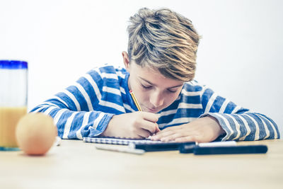 Close up view of student drawing with pencil. boy doing homework writing on a paper. kid hold pencil