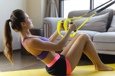 Side view of young woman exercising in gym