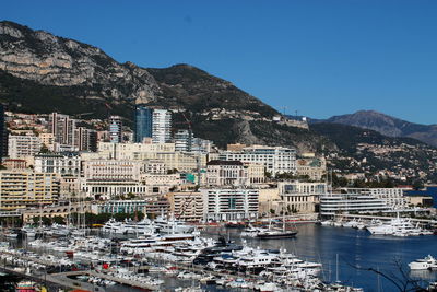 Sailboats in city by sea against clear sky