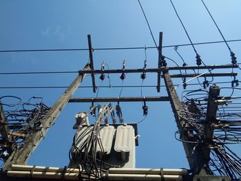 Low angle view of power lines against blue sky