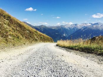 Road by mountains against sky