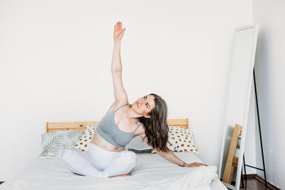 Young woman sitting on bed at home