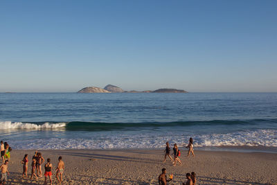 People at beach against clear sky