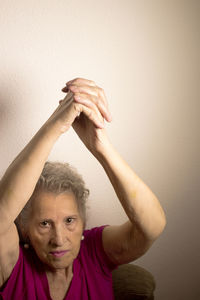 Portrait of woman exercising against wall