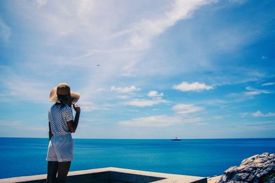 Rear view of woman wearing hat looking at sea against sky