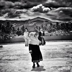 Rear view of woman standing on mountain against cloudy sky