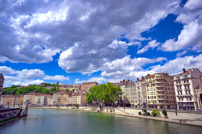 Bridge over river amidst buildings in city against sky