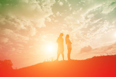 Silhouette friends standing against sky during sunset