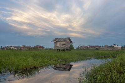 Built structure on field by buildings against sky