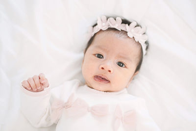 High angle portrait of baby girl lying on bed