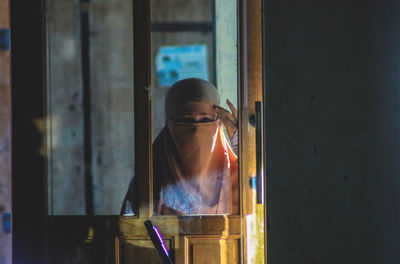 Portrait of woman looking through window