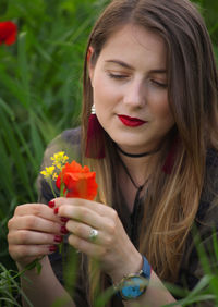 Close-up of woman holding flowers on field