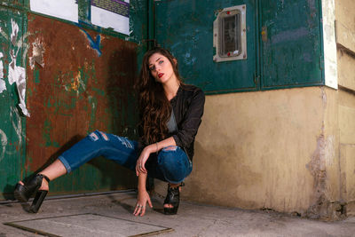 Portrait of young woman standing against wall