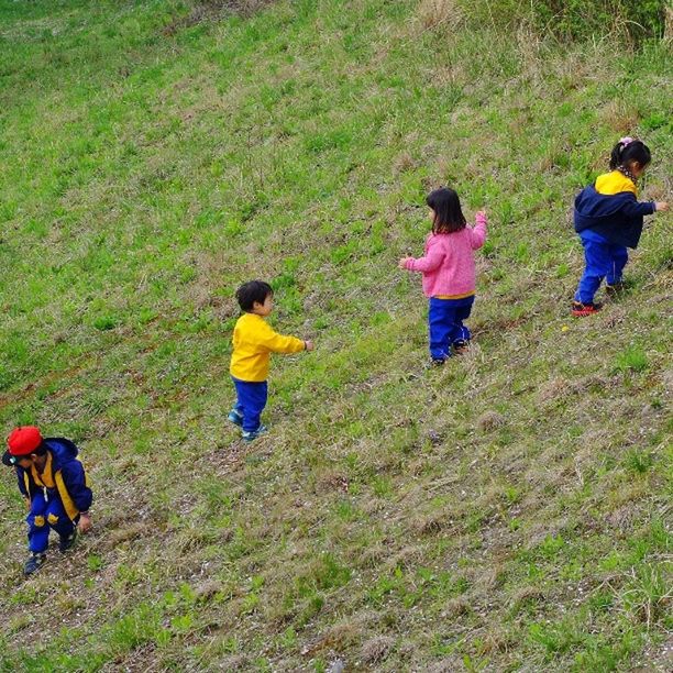 grass, leisure activity, lifestyles, boys, childhood, field, casual clothing, men, girls, togetherness, green color, full length, grassy, person, elementary age, rear view, bonding, landscape