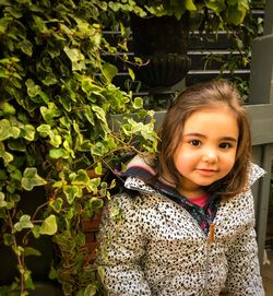 Portrait of cute smiling girl standing against plants