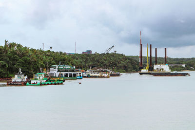 Boats in sea against cloudy sky