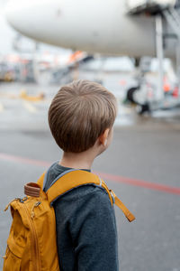 A little boy stands by the plane in line to land.