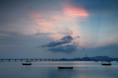 Silhouette boats moored in sea at sunset